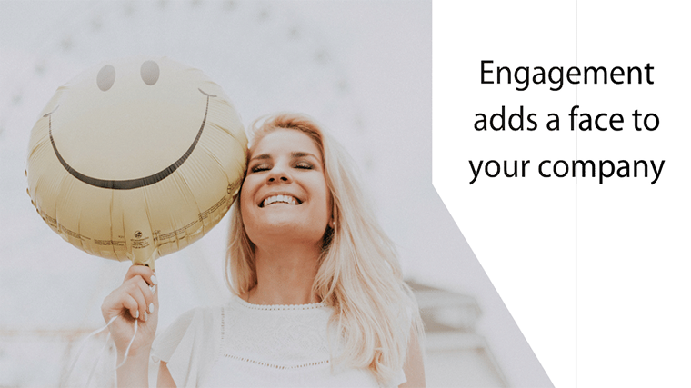 Image: a smiling blond woman with long hair and a white shirt holds a yellow, Mylar smiley face balloon sub header title text reads Engagement adds a face to your company